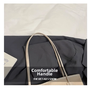 Detail of beige woven tote bag with smooth leather handle and refined stitching