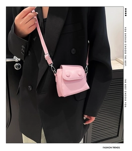 Detail of pink mini crossbody bag with round buckle accents and silver metal hardware