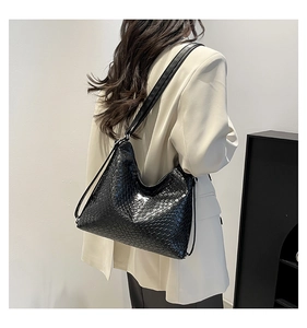 Model wearing a large black woven hobo shoulder bag with a stylish soft leather strap