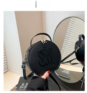 Detail of round black handbag with SM metallic logo and adjustable gold shoulder strap