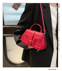 Dettaglio della borsa a sella in pelle rossa con fibbia dorata sulla modella