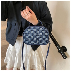 Détail du sac à bandoulière en denim bleu avec texture à carreaux effilochés et fermeture
