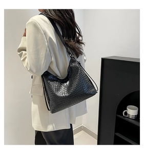 Macro detail of black woven leather hobo bag with glossy finish and dual shoulder straps