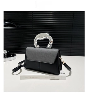 Detail of grey striped flap and irregular liquid silver metal handle on black crossbody bag