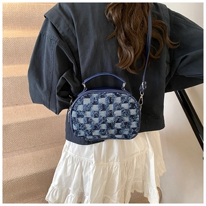 Detail of blue denim checkerboard bag featuring frayed fringe edges and leather handles
