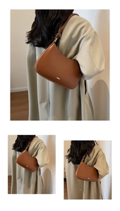 Detail view of a brown leather crescent shoulder bag featuring adjustable strap and logo