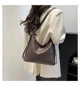 Close-up of a dark brown woven texture hobo bag with a silver butterfly buckle detail