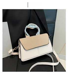 Detail of white leather handbag with beige woven flap and unique silver metal handle