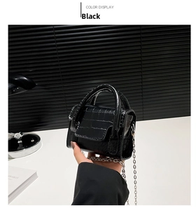 Detail of black faux crocodile leather mini bag with silver chain and top handle strap