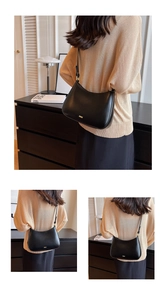 Detailed view of the black leather baguette bag featuring a gold logo and adjustable strap