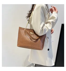 Close-up of brown leather woven tote bag featuring a gold chain strap and metal buckle