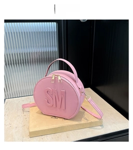 Detailed macro view of pink round crossbody bag with 3D embossed SM letters and gold zipper