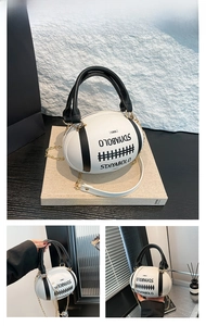 Detail of rugby-shaped white handbag with black handles and gold chain strap close-up
