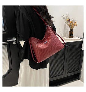 Detail of red woven texture handbag with silver butterfly charm on a slim shoulder strap