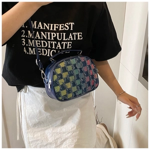 Détail du sac bandoulière en cuir bleu marine avec tissu à carreaux effiloché et sangle