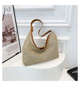 Detailed view of woven tote bag with brown leather trim on white display stand
