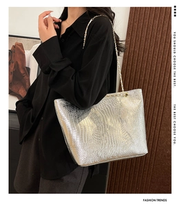 Silver crocodile texture tote bag with gold chain strap on model's shoulder