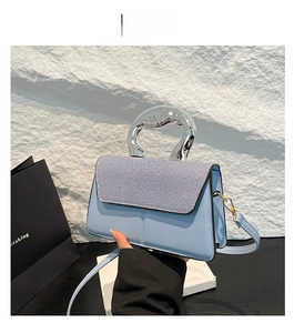 Detail of light blue crossbody bag with striped fabric flap and silver metal handle