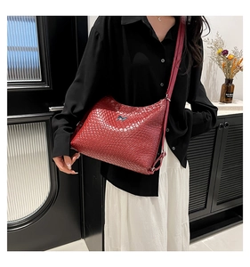 Deep red woven texture crescent bag with silver bow buckle worn by model outdoors