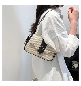 Détail du sac à bandoulière tissé beige avec bordure noire et boucle dorée chic