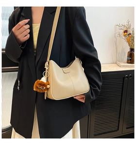 Détail du sac seau en cuir beige avec un charmant pendentif lion en peluche marron