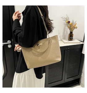 Detail of khaki tote bag with woven texture, metal chain strap and deer charm