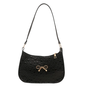 Minimalist black shoulder bag with textured dot pattern and golden bow accent detail