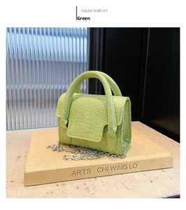 Detail of green crocodile pattern mini bag with thick handle and silver chain strap