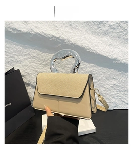 Detail of khaki leather handbag featuring straw texture flap and silver metal handle