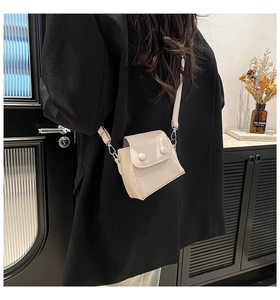 Detail of a chic cream mini crossbody bag with double round buttons on leather flap