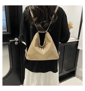 Detail of beige hobo backpack with woven texture and gold butterfly charm on the back
