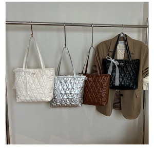 Détail de quatre sacs fourre-tout matelassés en blanc, argent, marron et noir avec nœuds
