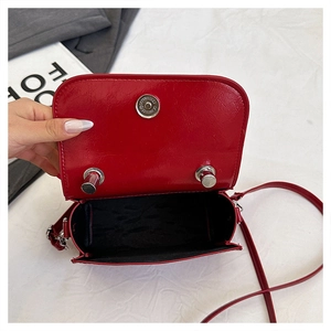 Detail of red glossy leather crossbody bag with silver magnetic snap and interior lining