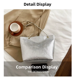 Close-up of silver crocodile embossed tote bag with gold chain strap and glossy leather finish