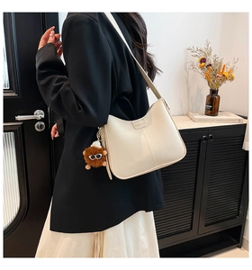 Détail du sac seau crème avec logo FASHION et pendentif en peluche pour un look chic