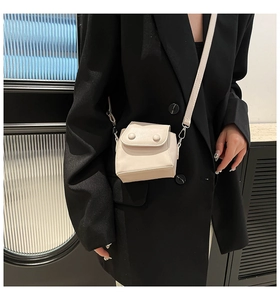 Detail of cream white mini crossbody bag with double round buckles on model
