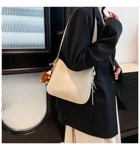 Sac hobo chic crème avec un pendentif en peluche et détail étiquette mode