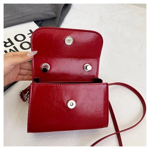 Detail of red patent leather square bag showing silver magnetic closure and interior