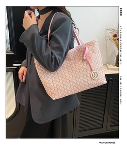 Detail of pink tote bag with M-letter jacquard pattern and metal pendant on shoulder
