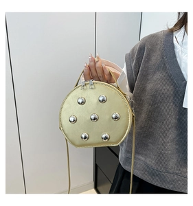 Détail du sac rond doré champagne avec clous argentés et fermeture éclair double design