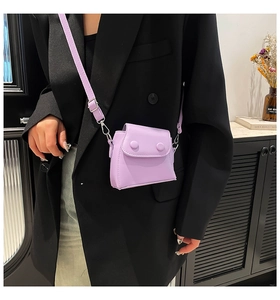 Close-up of a light purple mini crossbody bag worn over a black blazer for styling