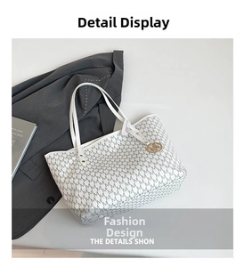 Detailed view of white monogram tote bag with gold M-logo pendant on a grey blazer