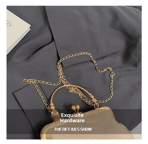 Detail of shell-shaped woven bag showing light gold frame closure and metal chain