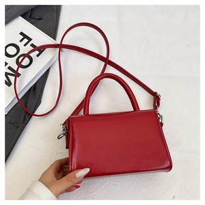 Close-up of bright red patent leather handbag with silver hardware and top handle