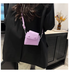 Detail view of a purple mini square crossbody bag worn by a model in a stylish interior