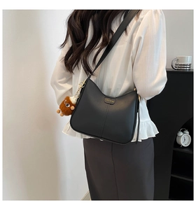 Détail du sac seau demi-lune noir avec lettrage doré et charmant pendentif en peluche