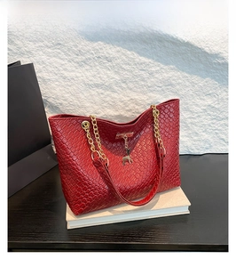 Detail of red woven tote bag with gold chain straps and a deer metal charm accent