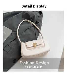Close-up of cream white shoulder bag featuring a polished gold heart-shaped metal clasp