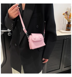 Close-up of pink mini crossbody bag with round button flap and silver metal hooks