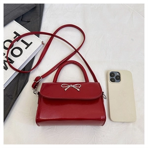 Top view of red patent leather mini handbag with silver bow buckle and shoulder strap